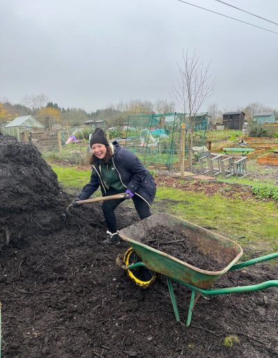 Amy Andrews shovels fresh soil into a wheelbarrow